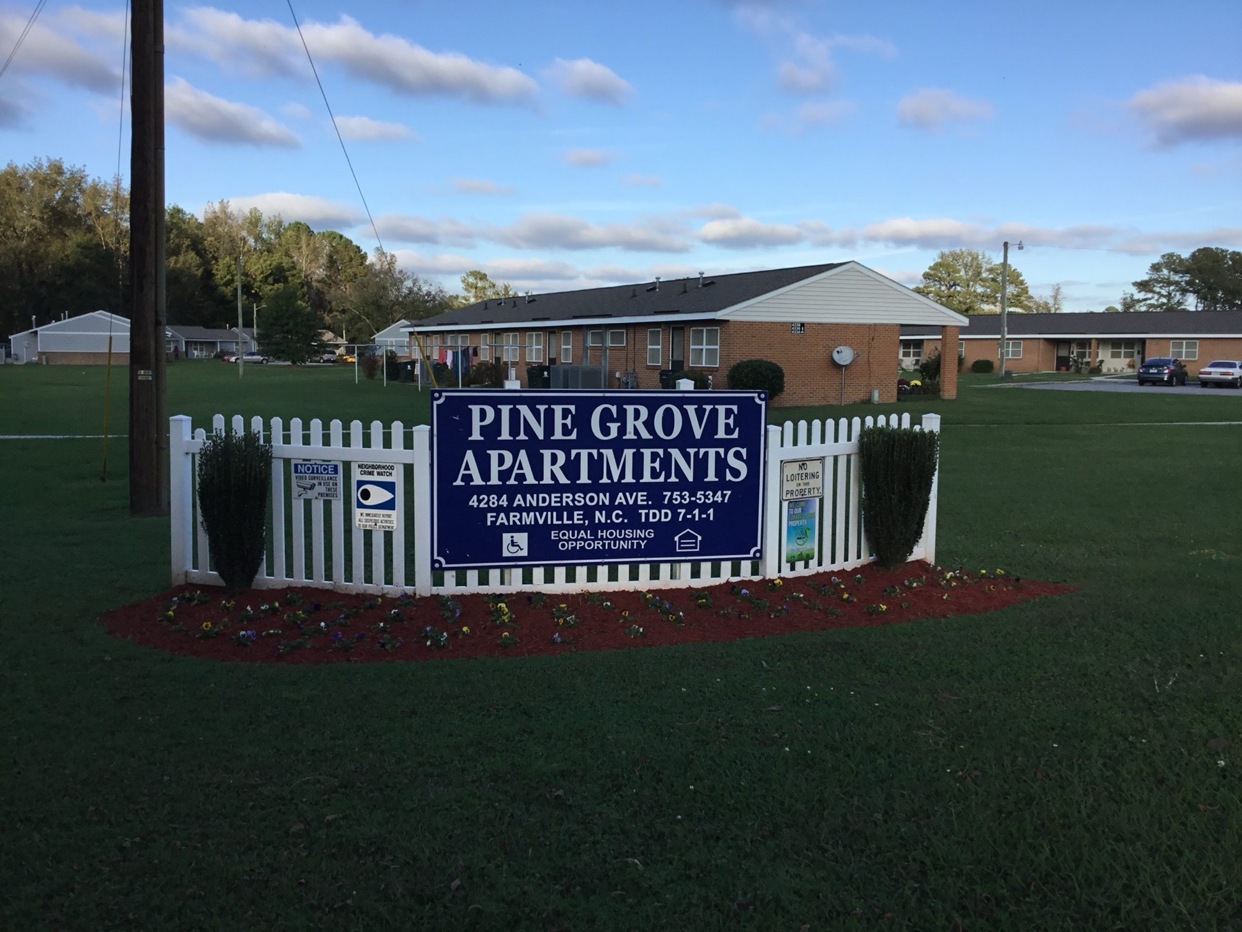 Pine Grove Apartments sign in front of brick apartment buildings